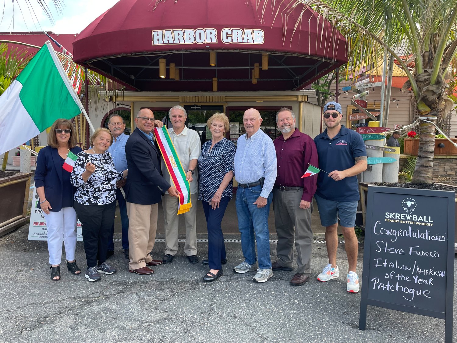 Past grand marshals, organizers of the festival, Greater Patchogue Chamber of Commerce executive director David Kennedy and last year’s grand marshal Joe Brandi gathered at Mark Miller’s Harbor Crab to pass the sash to Steve Fuoco